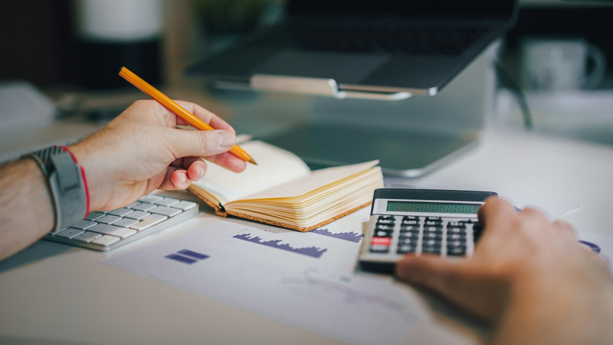 A bookkeeper working with a calculator and notebook