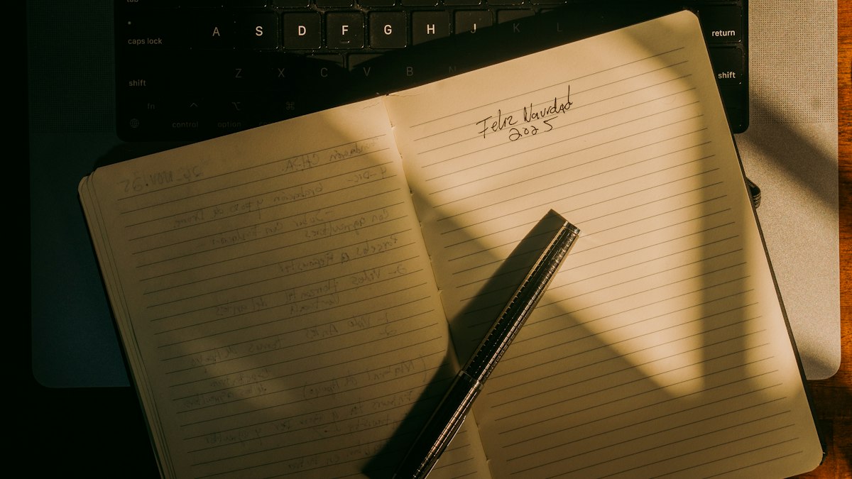An open notebook and pen on a laptop keyboard