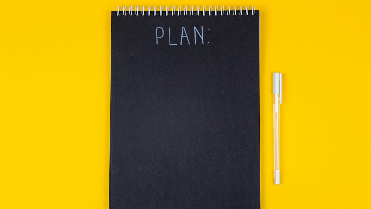 A notebook with the word PLAN on a yellow background