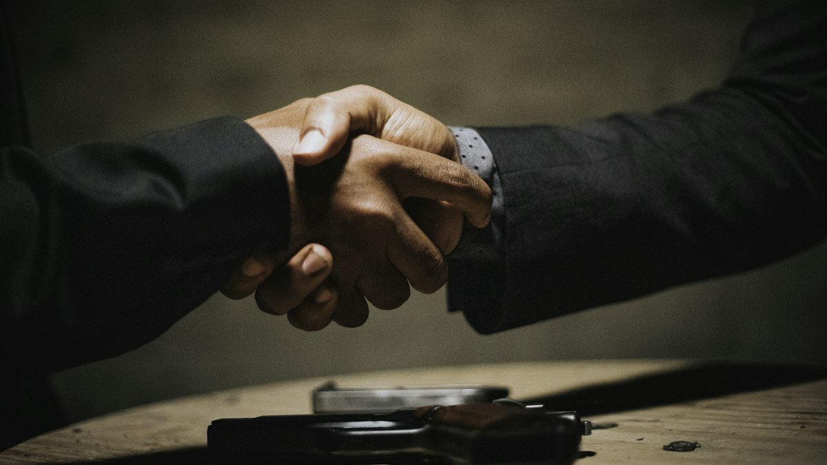 Two people shaking hands over a table