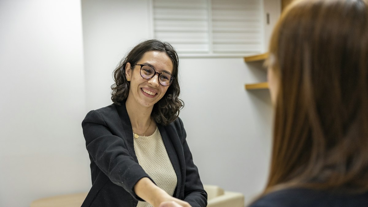 A candidate greeting an interviewer across a table