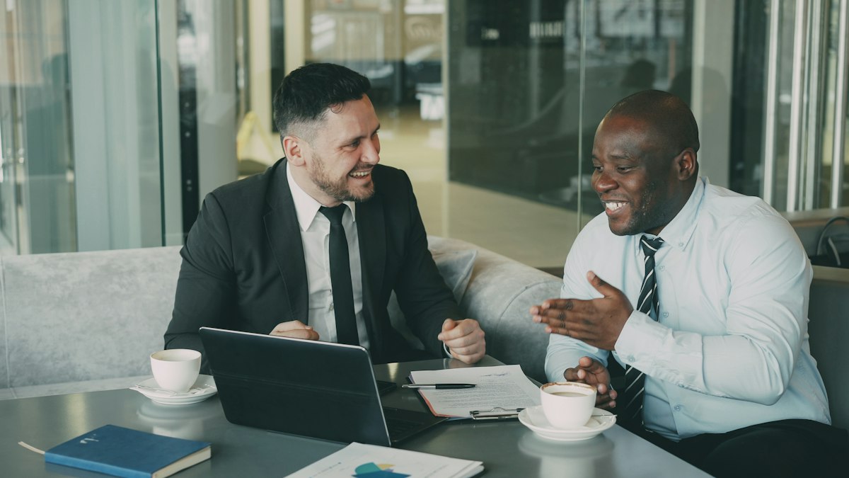 Two business partners laughing during a meeting at a café