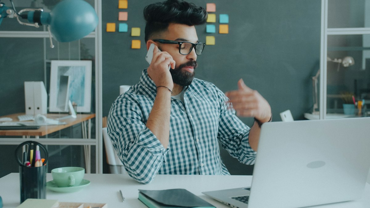 A man talking on the phone at his desk