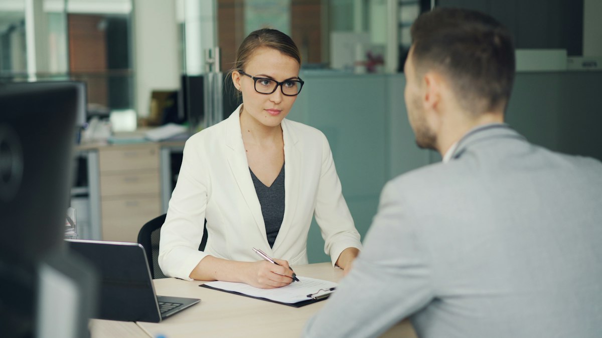 A woman interviewing a man at a desk