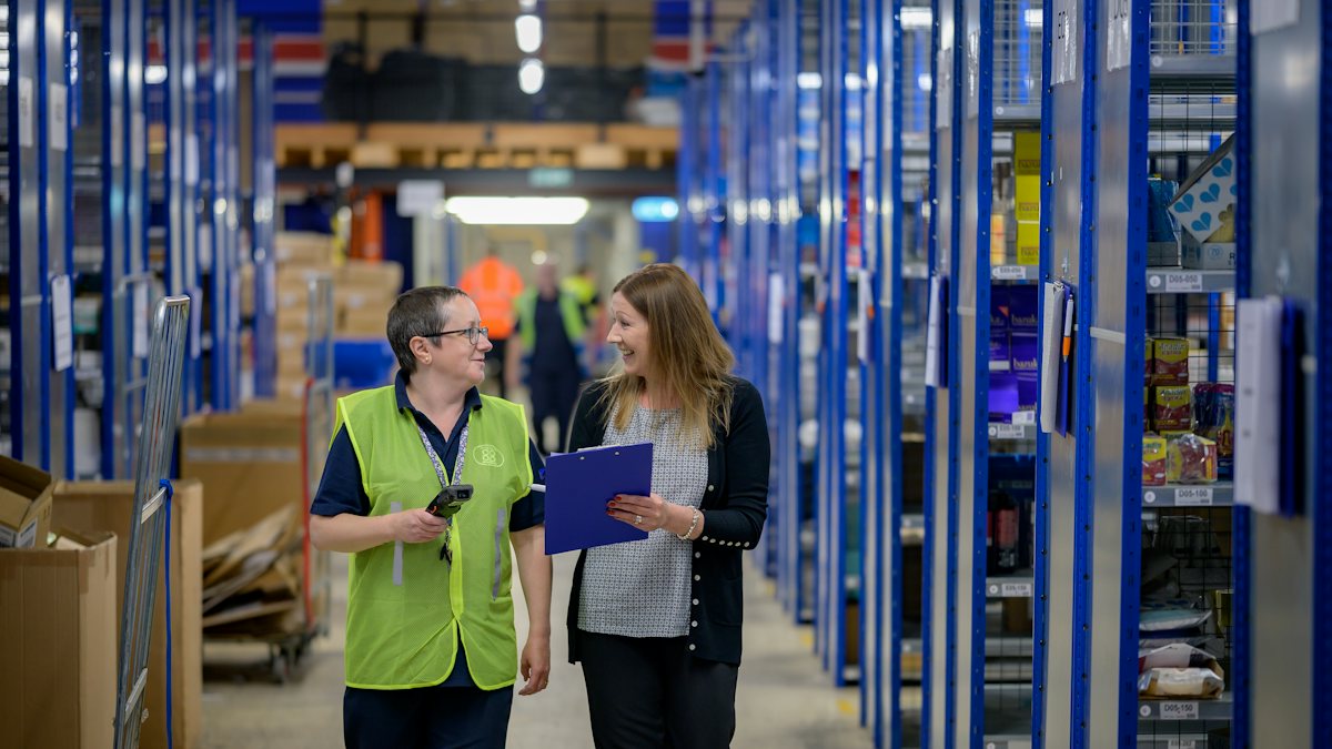 Two women walking through a warehouse aisle