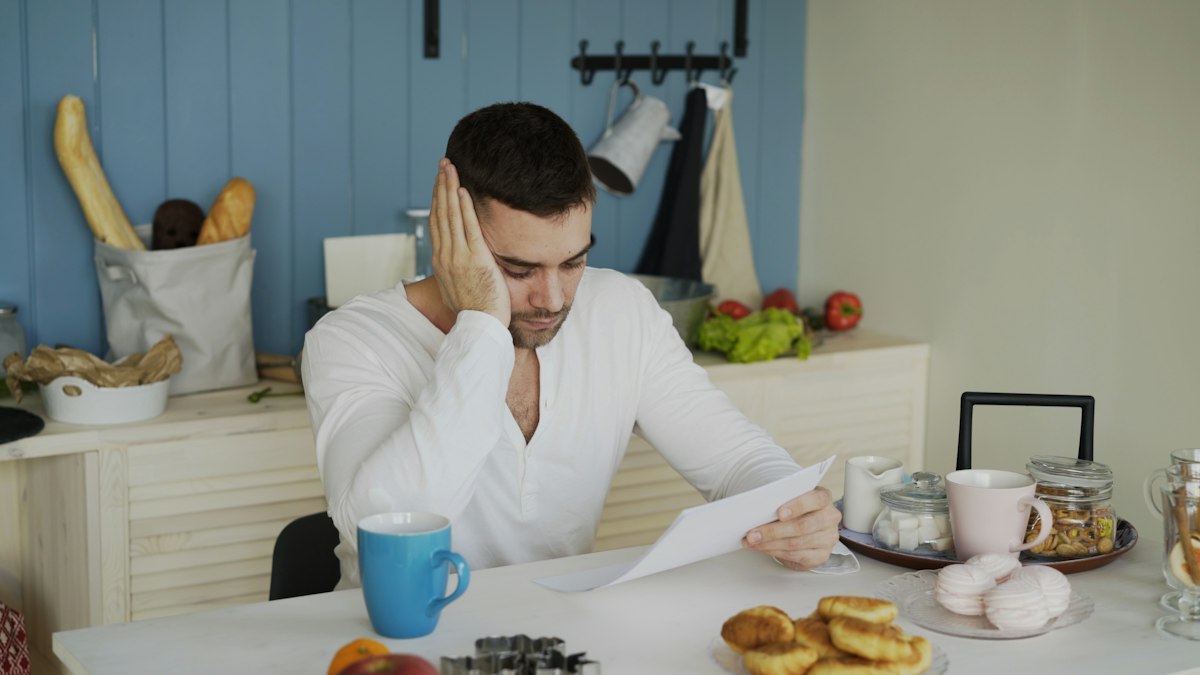 A man reading a quote at his kitchen table, head in hand