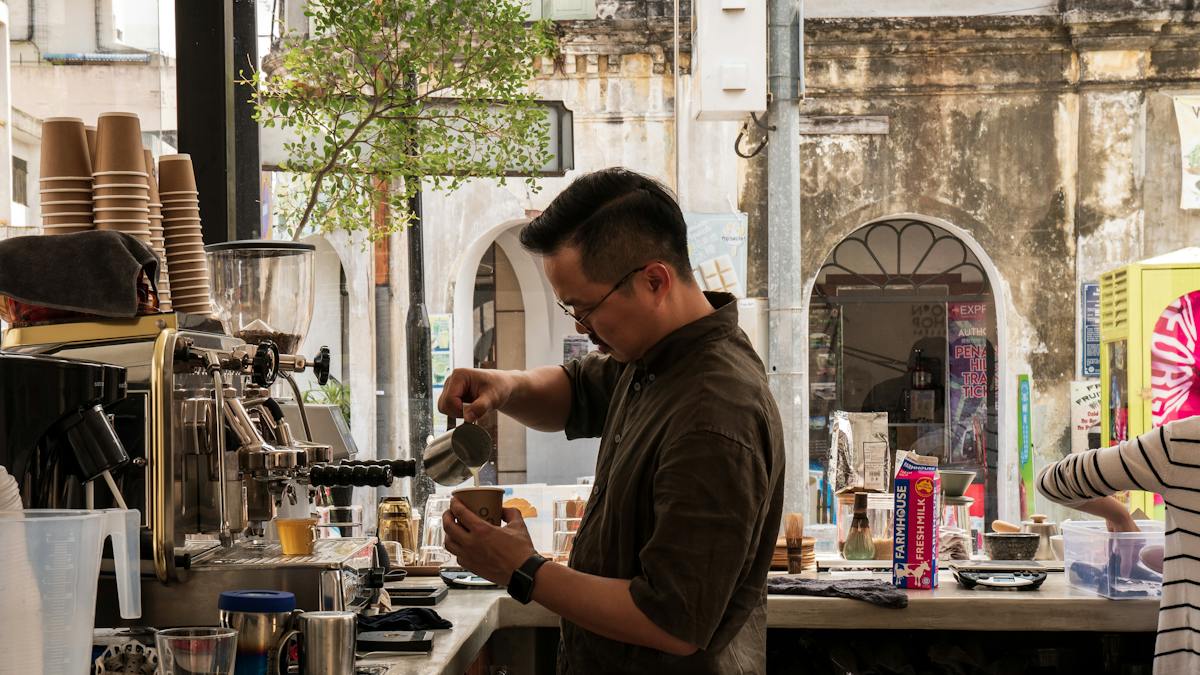 A barista pouring steamed milk into a coffee cup