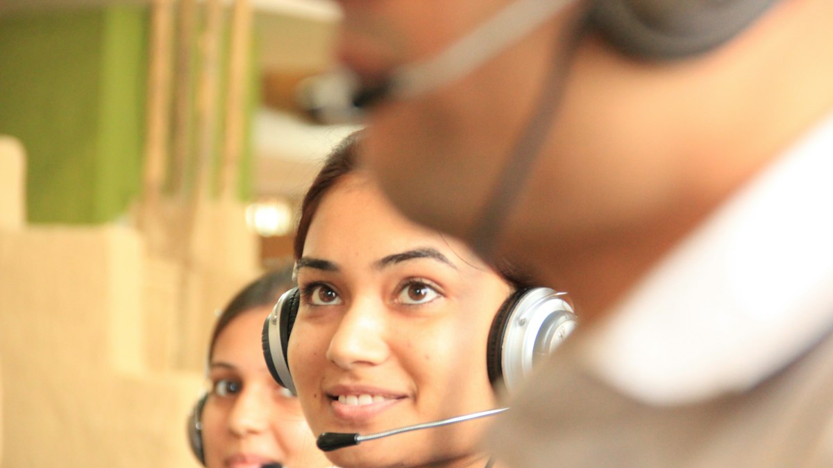 Two women wearing headsets in a bright office