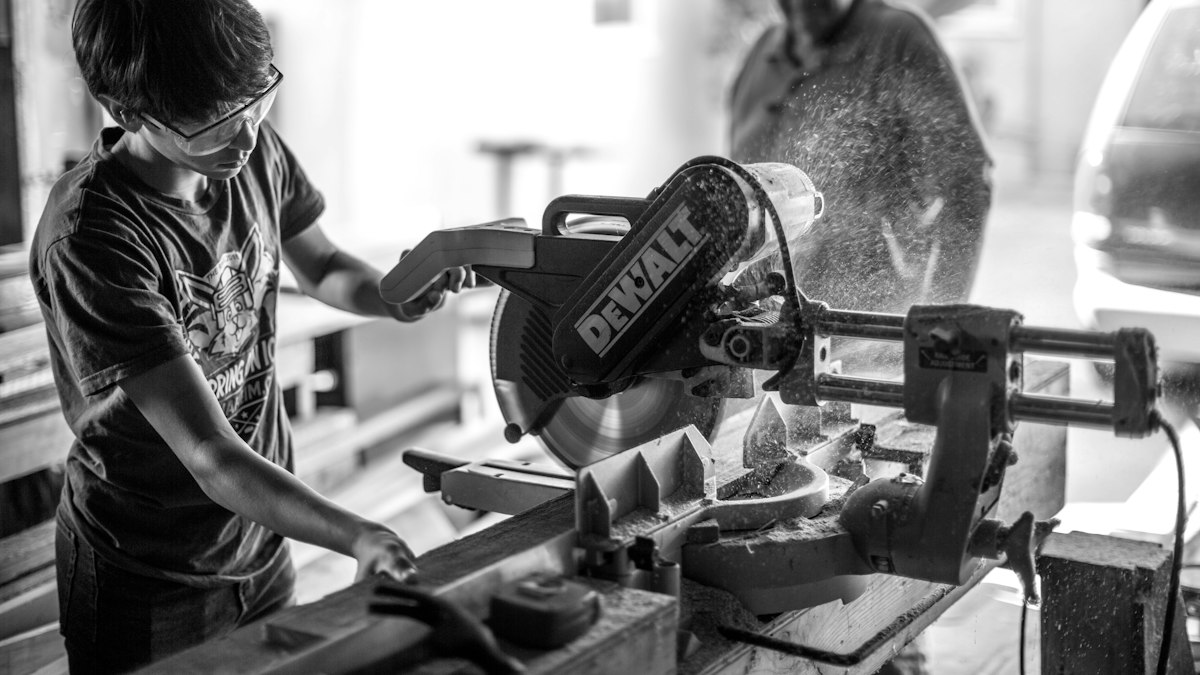 A young person learning to use a mitre saw